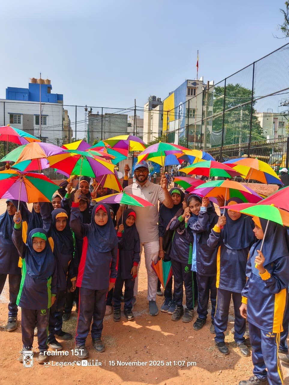 Students with colourful umbrellas on the sports ground
