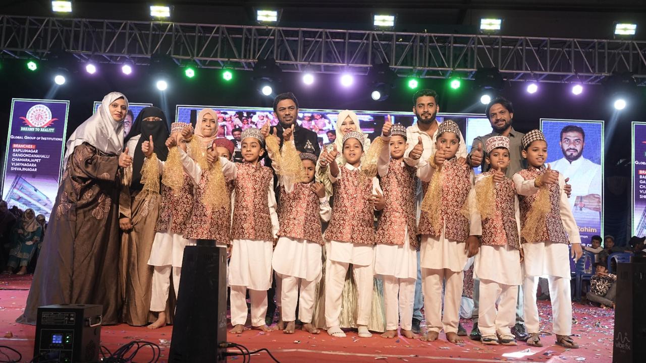 Young performers pose with teachers on stage